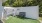 a white shed with a bench and a metal fence